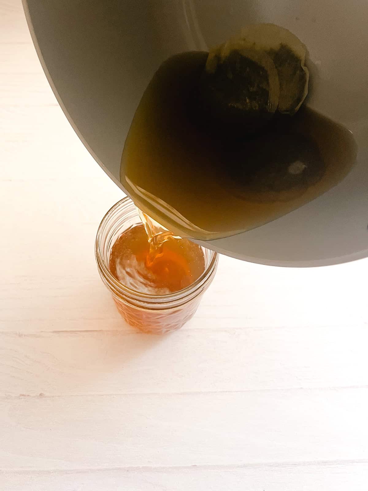 Pouring green tea hair rinse from a saucepan into a jar.