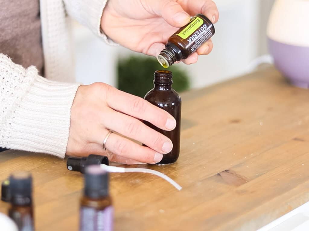 Dropping essential oils into an amber glass bottle.