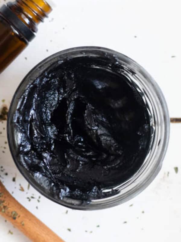 A jar of drawing salve with a bottle of essential oils next to it.