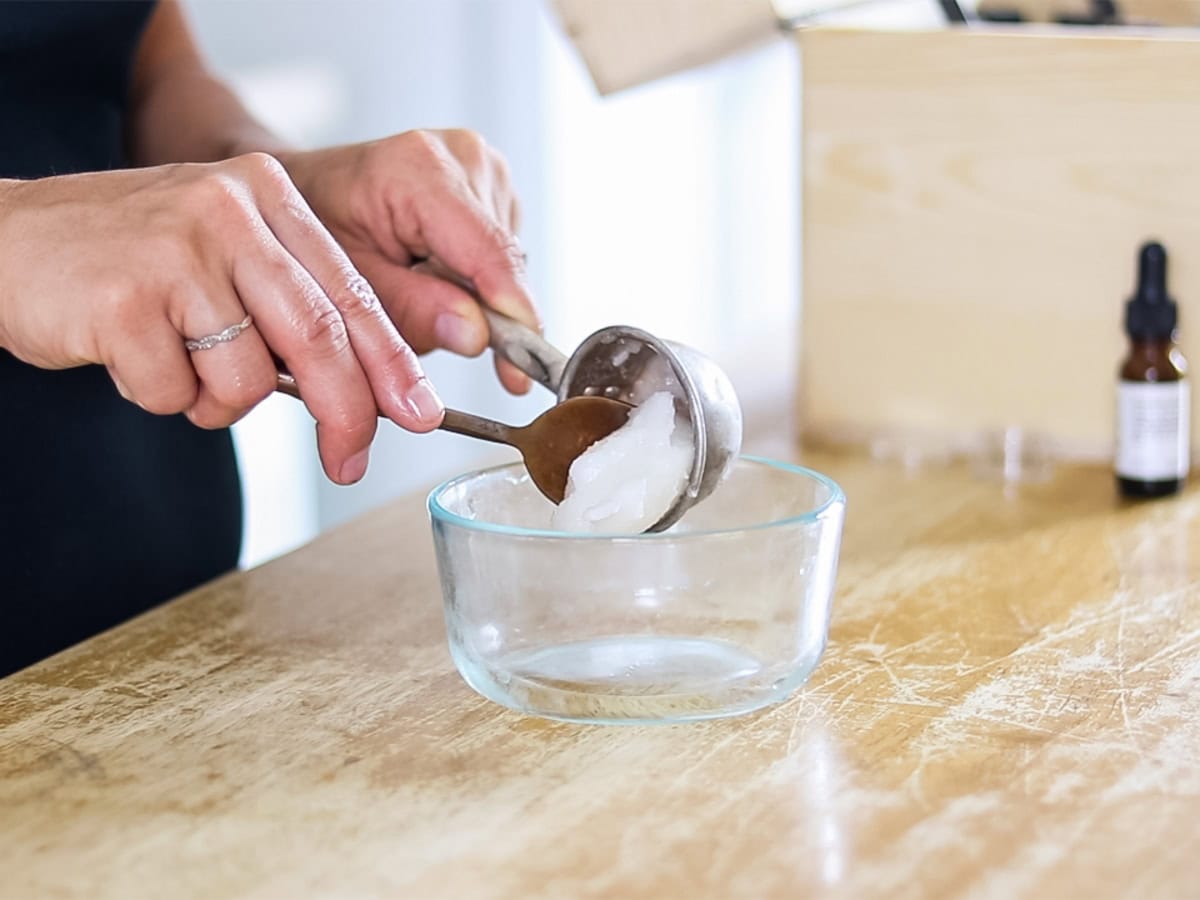 Scooping coconut oil into a glass bowl.