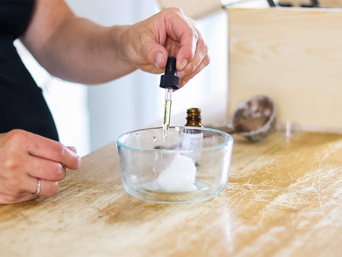 Dropping vitamin E oil in a glass bowl with coconut oil.