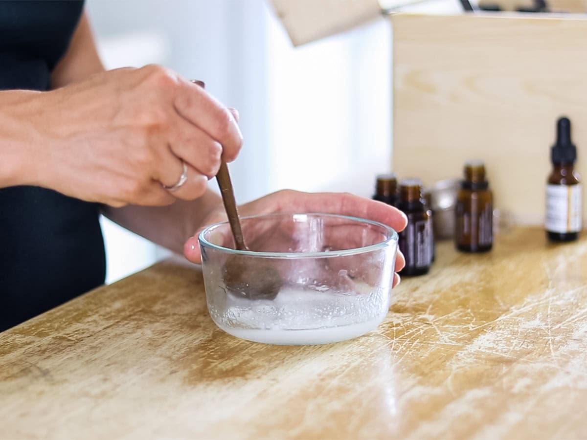 Stirring homemade eye cream in a small glass bowl.
