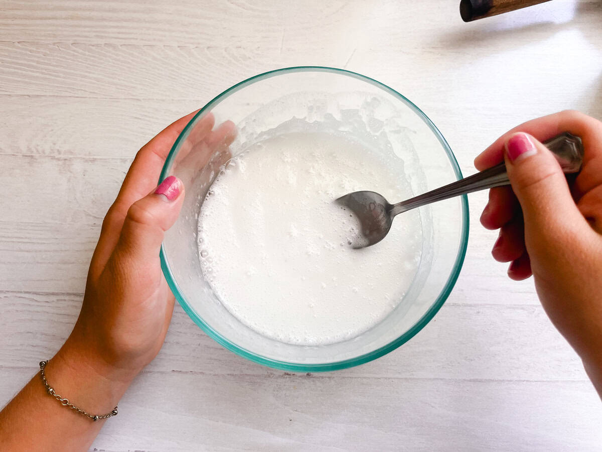 Stirring DIY bathtub cleaner in a glass bowl. 