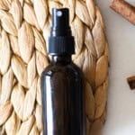 An amber bottle of hand sanitizer spray on a wicker placemat.
