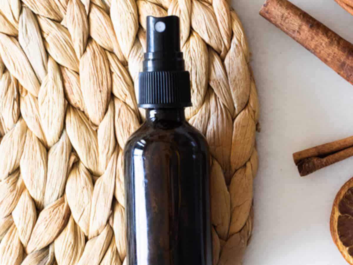 An amber bottle of hand sanitizer spray on a wicker placemat.