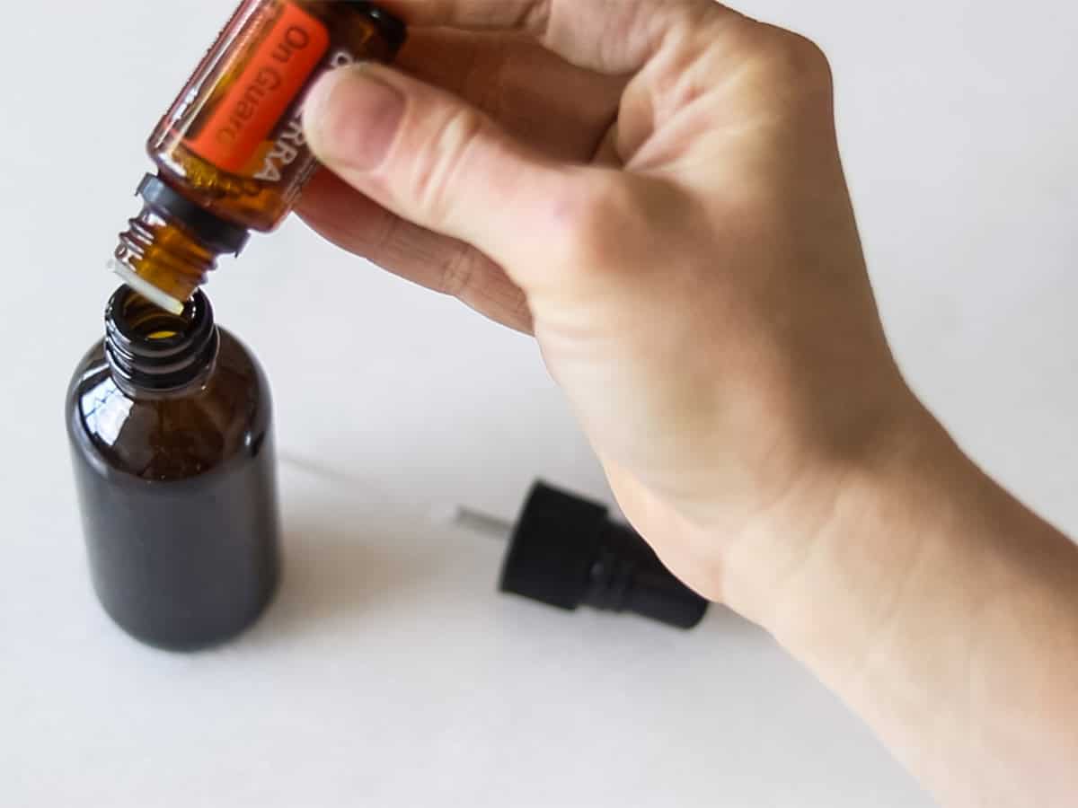 Dropping essential oils into a glass spray bottle.
