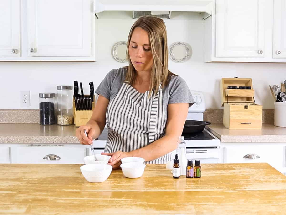 Stirring rosemary shampoo in a white bowl.