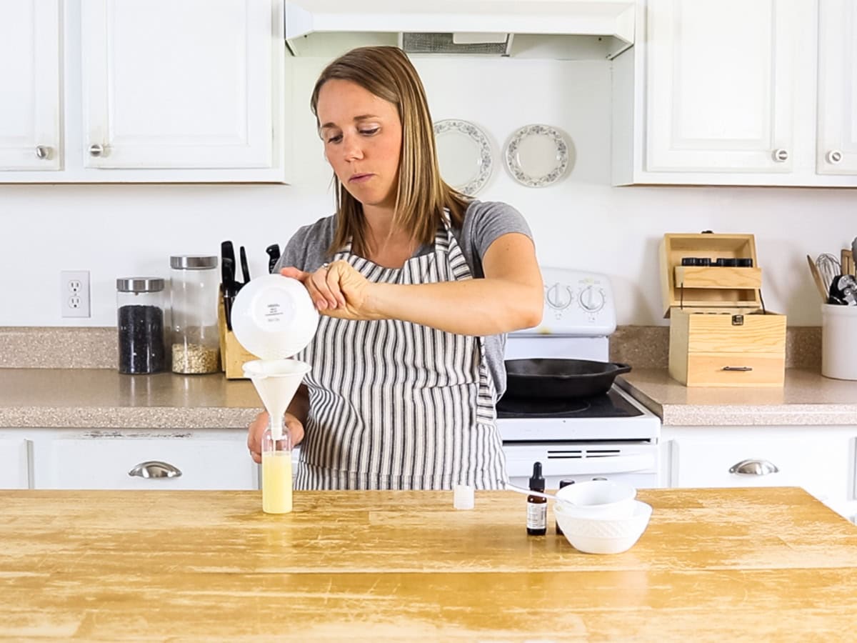 Pouring rosemary shampoo into a shampoo bottle with a large funnel.