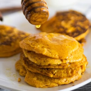 A white plate with stacks of pumpkin pancakes on it.