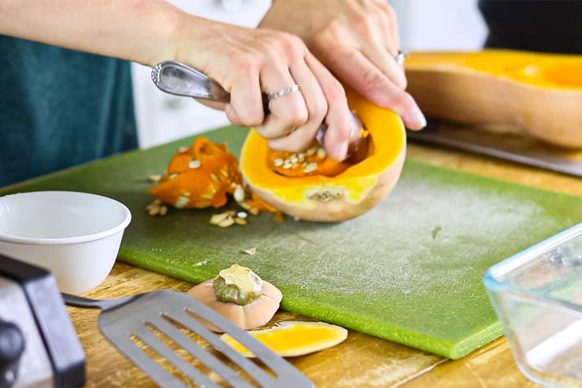 Scooping seeds out of a half of a pumpkin.