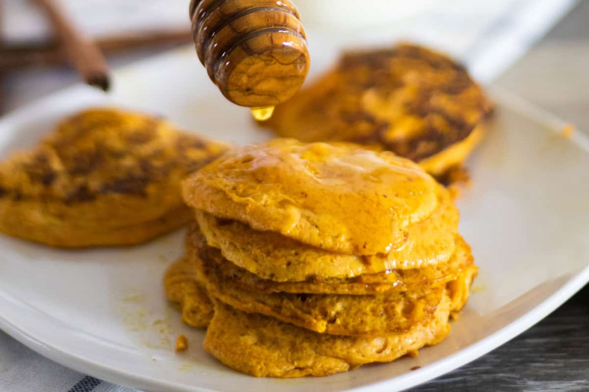 A white plate with stacks of pumpkin pancakes on it.