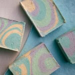 Colorful, swirled olive oil soap bars spread out on a blue towel.