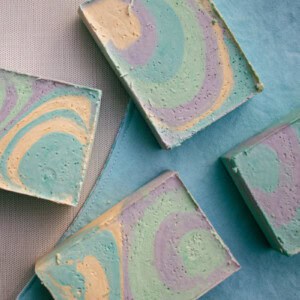 Colorful, swirled olive oil soap bars spread out on a blue towel.