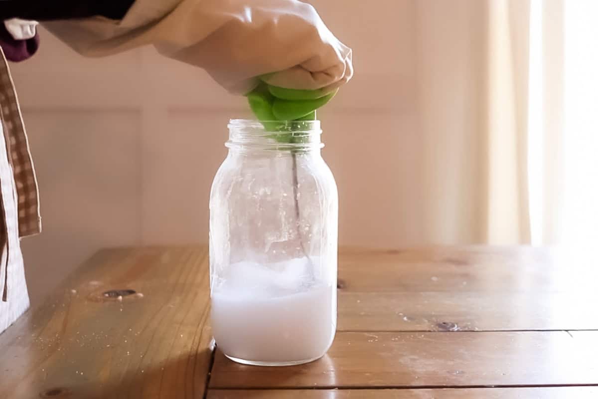 Stirring lye and water in a mason jar with gloves on. 