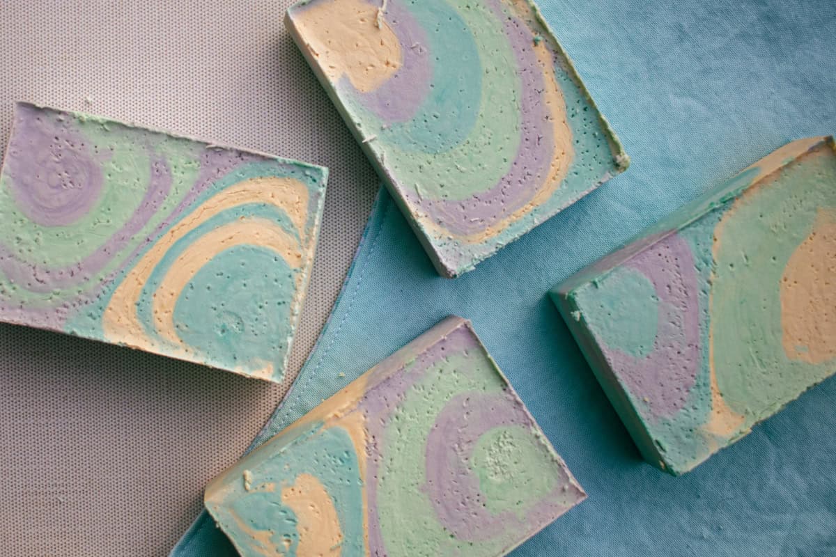 Colorful, swirled olive oil soap bars spread out on a blue towel.
