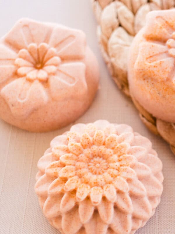 Flower-shaped orange soap bars on a wicker placemat.