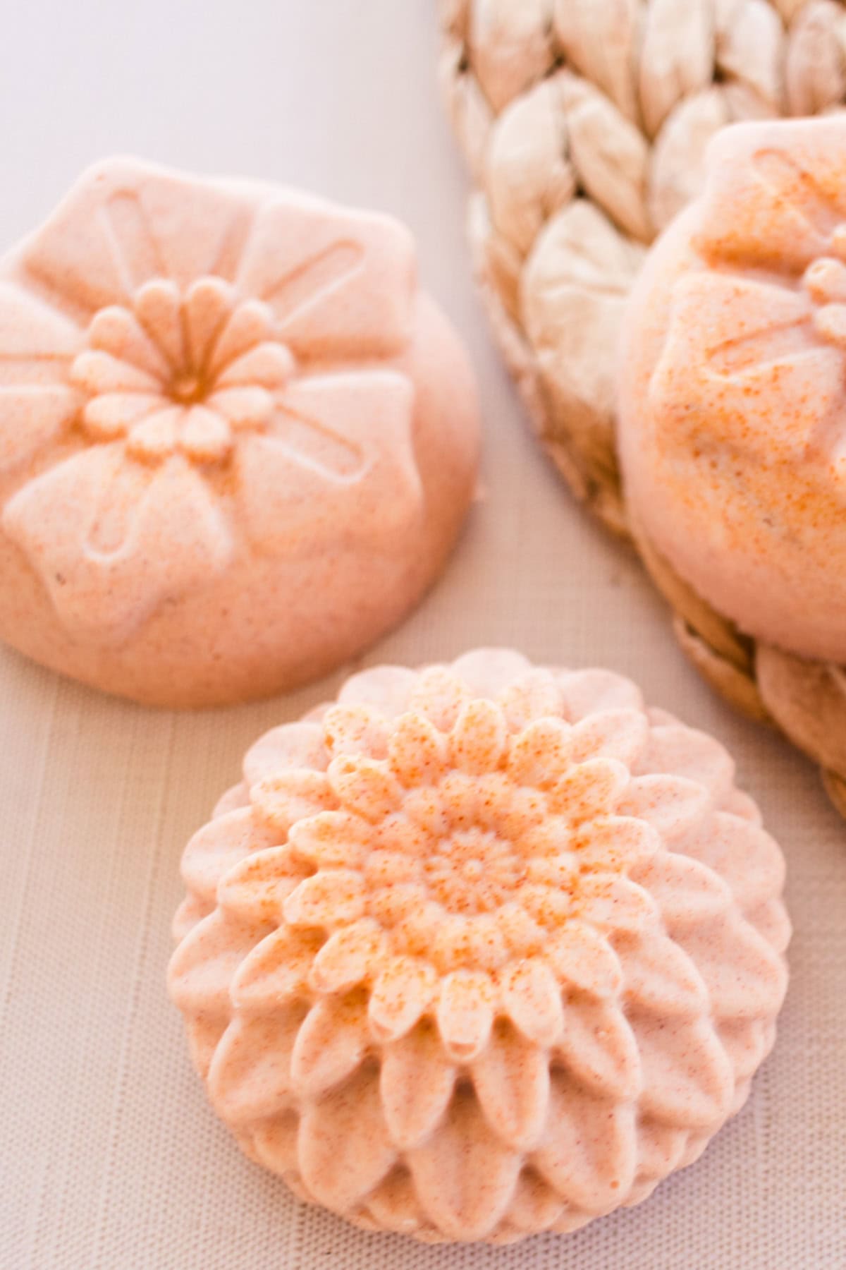 Flower-shaped orange soap bars on a wicker placemat. 