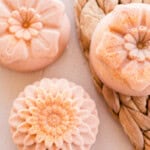 Flower-shaped orange soap bars on a wicker placemat.
