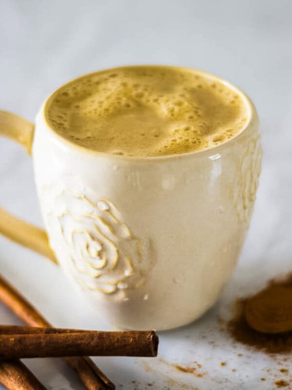A mug of whole30 pumpkin spice latte with cinnamon sticks.