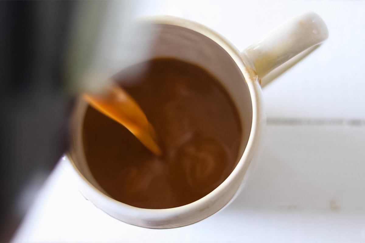 Pouring a whole30 pumpkin spice latte into a large mug.