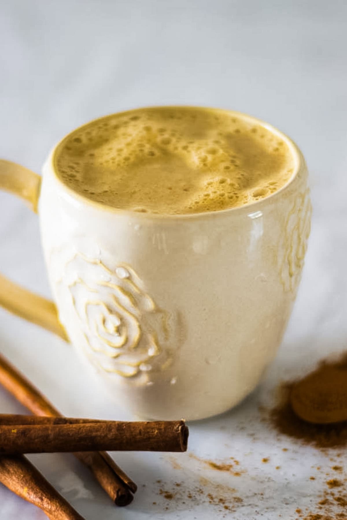 A mug of whole30 pumpkin spice latte with cinnamon sticks.