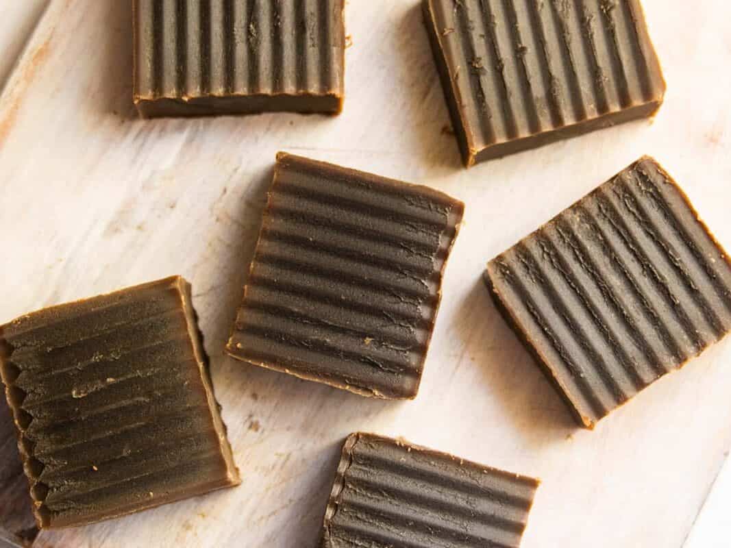 Bars of homemade pine tar soap spread out on a wooden table.
