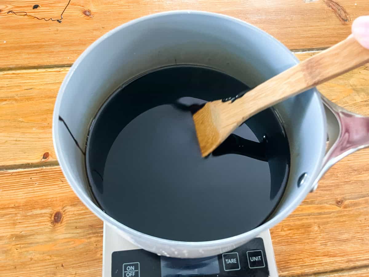 A pot of melted oils and pine tar on a digital scale. 