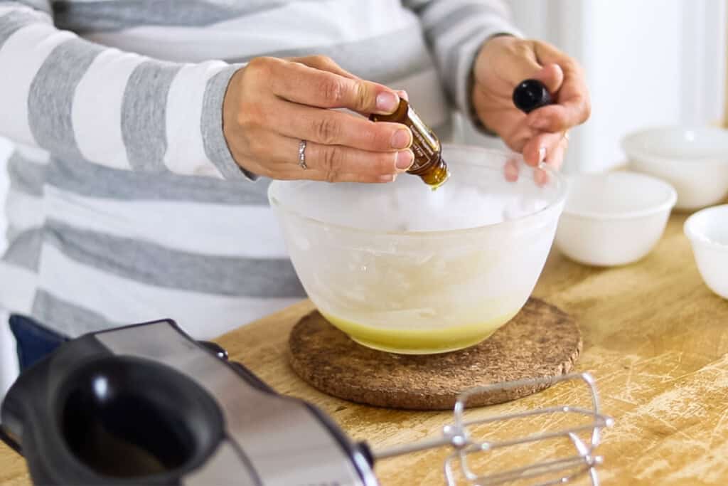 Adding essential oils to a bowl of beard balm ingredients.