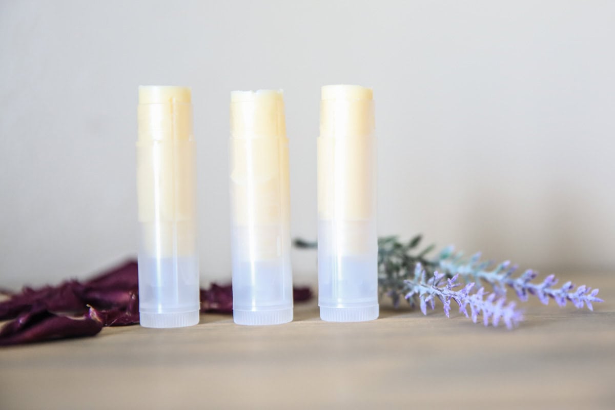 Freshly made lip balm on wooden table with dried lavender springs.