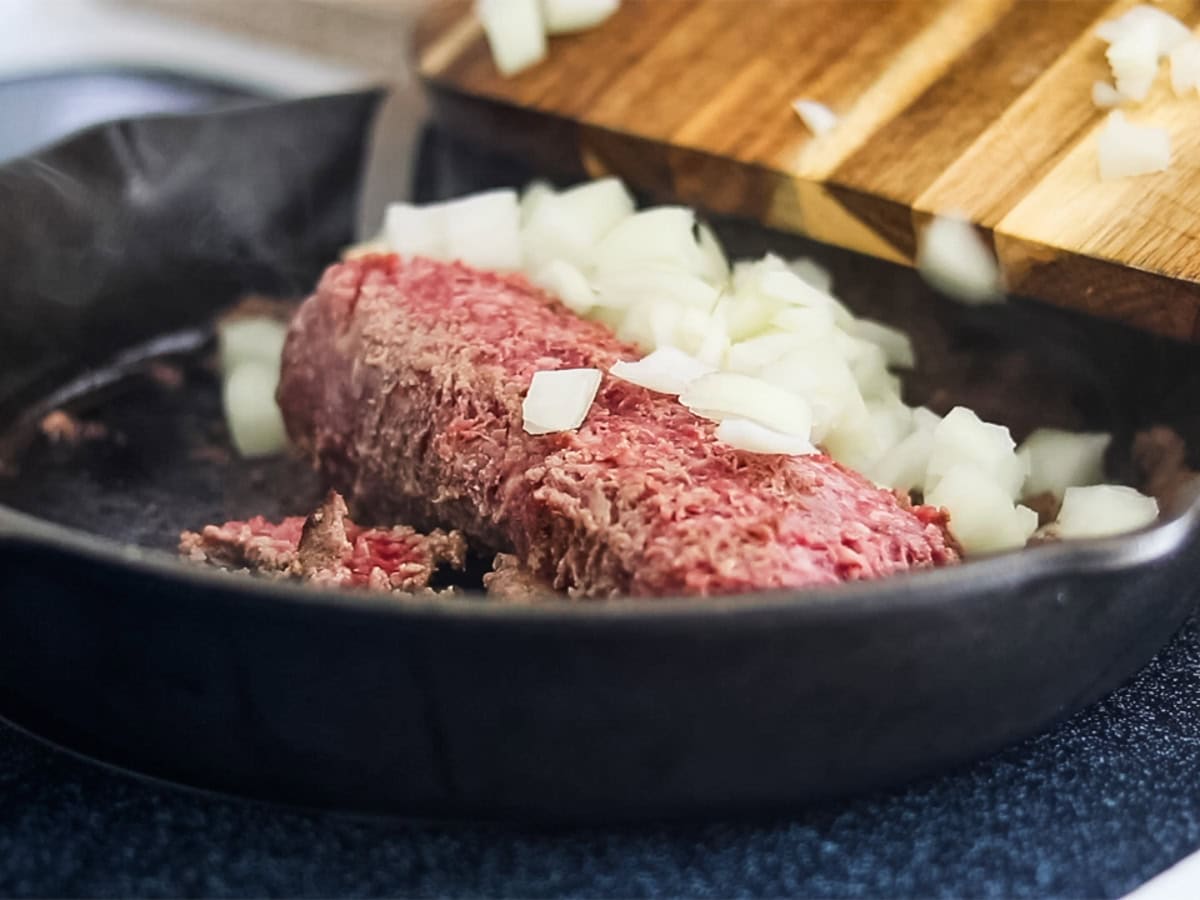 Browning ground beef with onions in a cast iron skillet. 