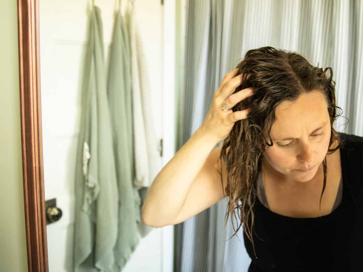 Massaging baking soda rinse into hair in a bathroom. 