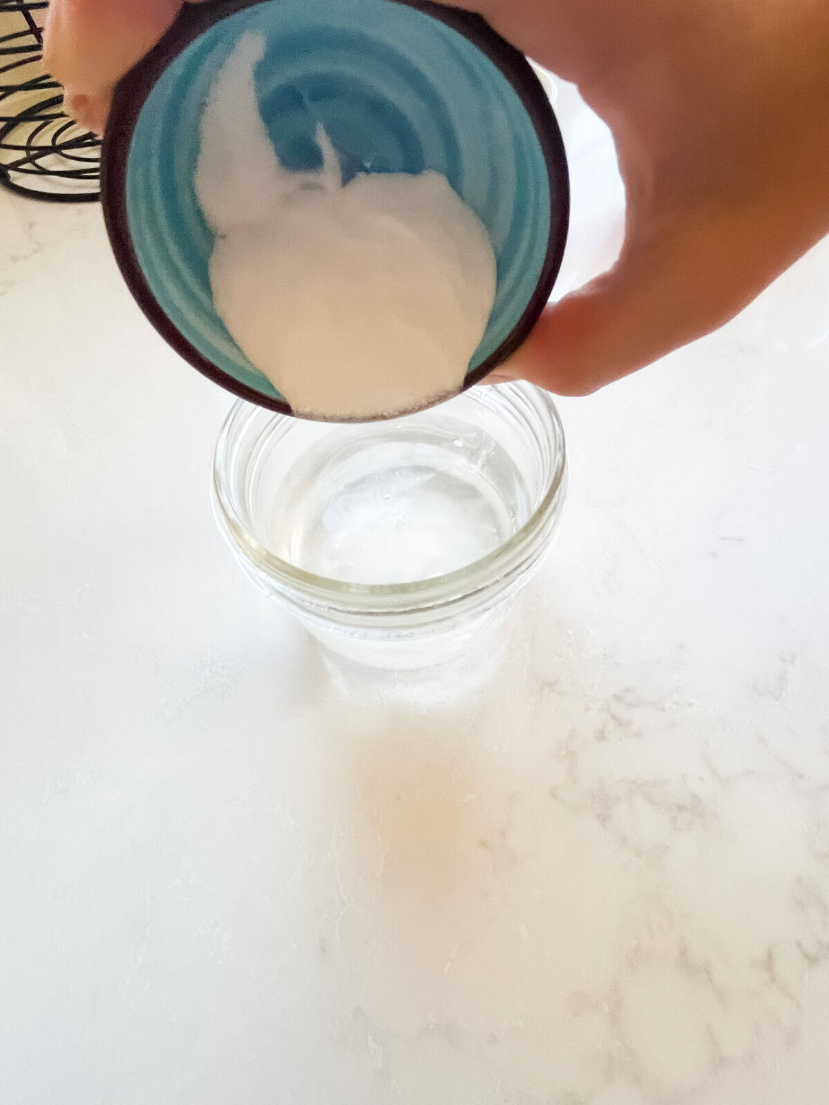 Pouring baking soda into a glass jar of water. 