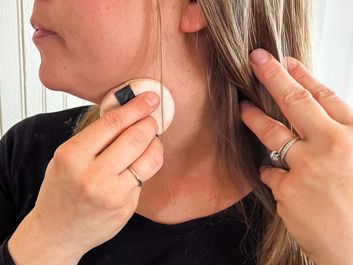 Applying body powder to the neck and jawline with a powder puff.