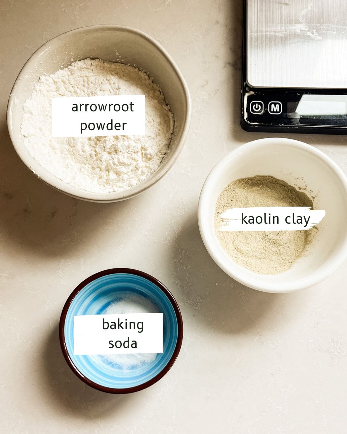 DIY body powder ingredients labeled on a white background with a digital scale.