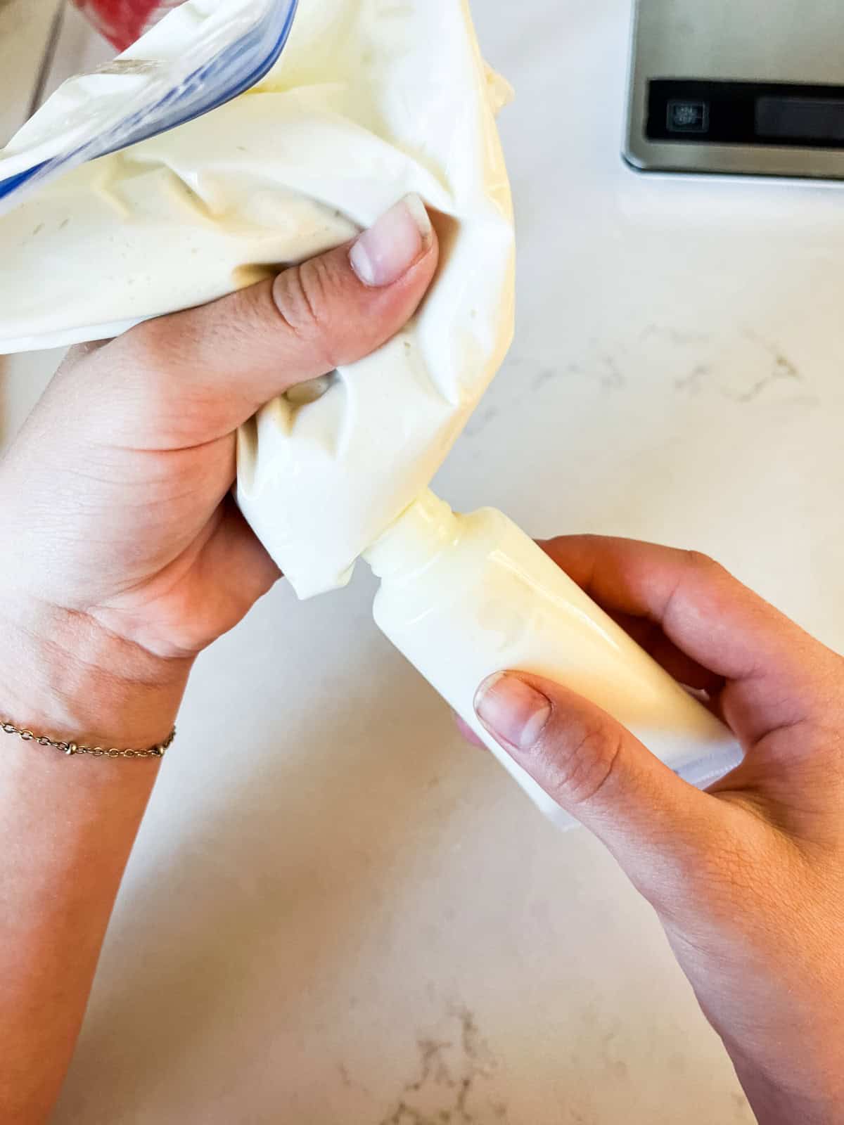 Squeezing homemade lotion out of a plastic bag into a tube container.