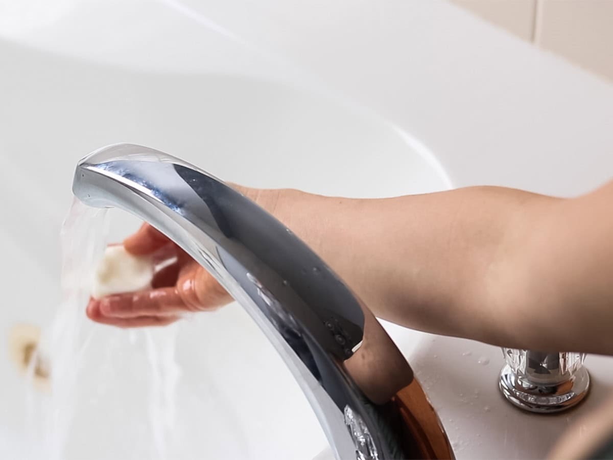 Running warm water over a bubble bath bar. 