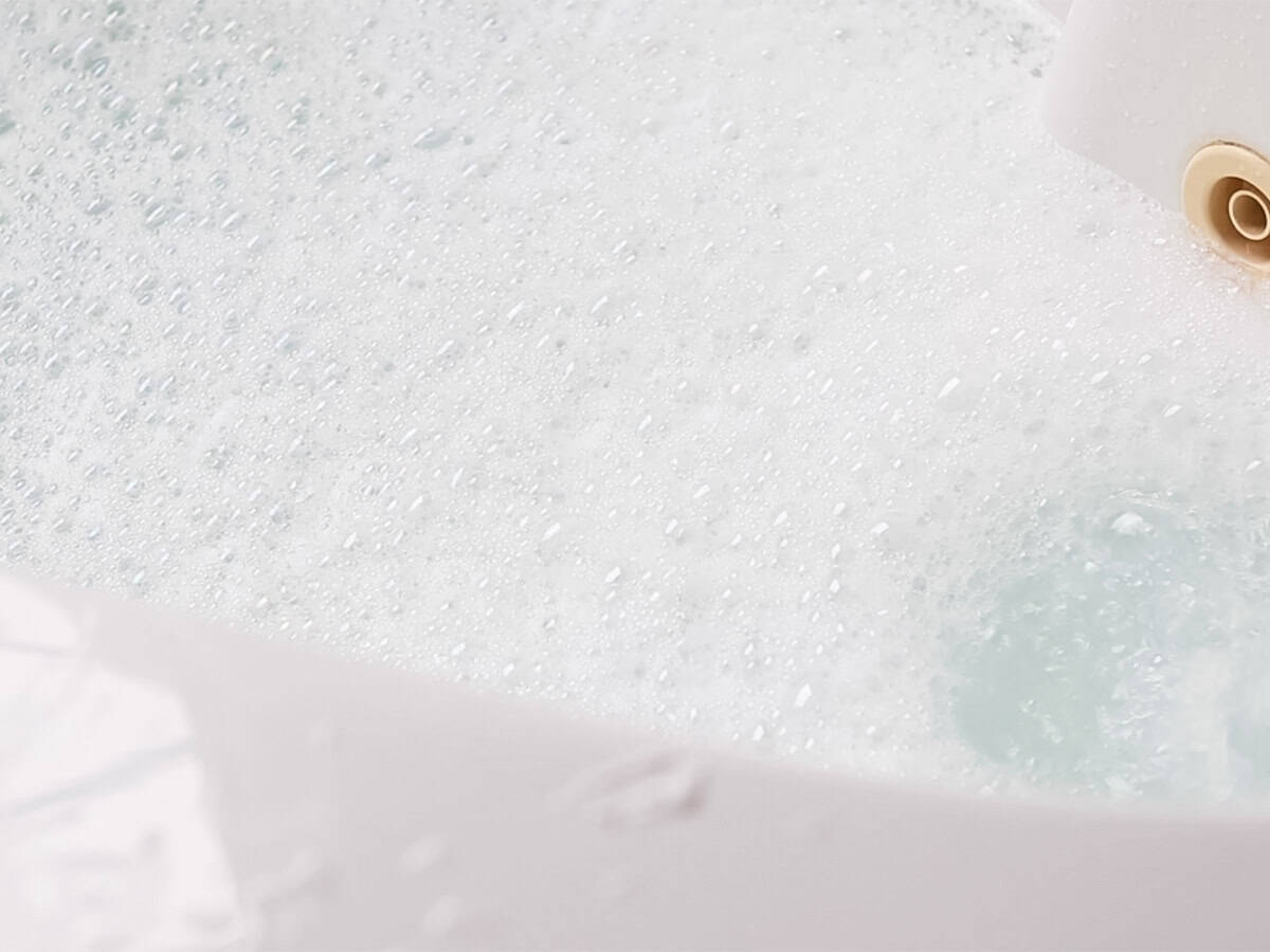 A bathtub filled with soapy bubble bath water. 