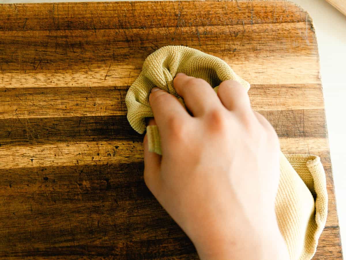 Rubbing wood balm into a wooden cutting board with a soft cloth. 