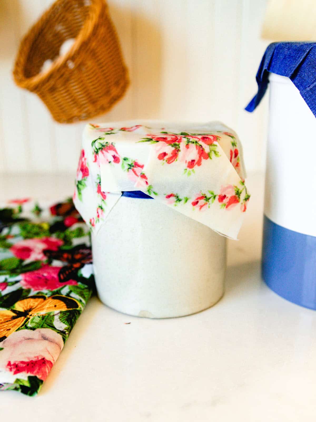 A homemade beeswax wrap covering a crock in a kitchen.