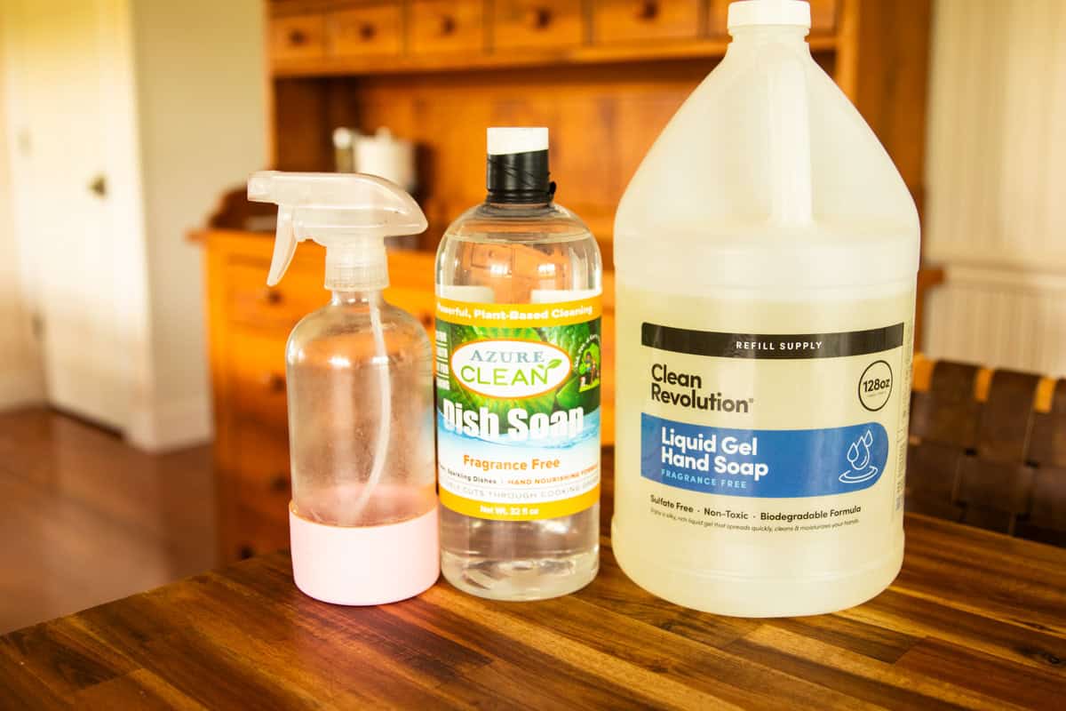 A glass spray bottle and two bulk bottles of cleaning ingredients.