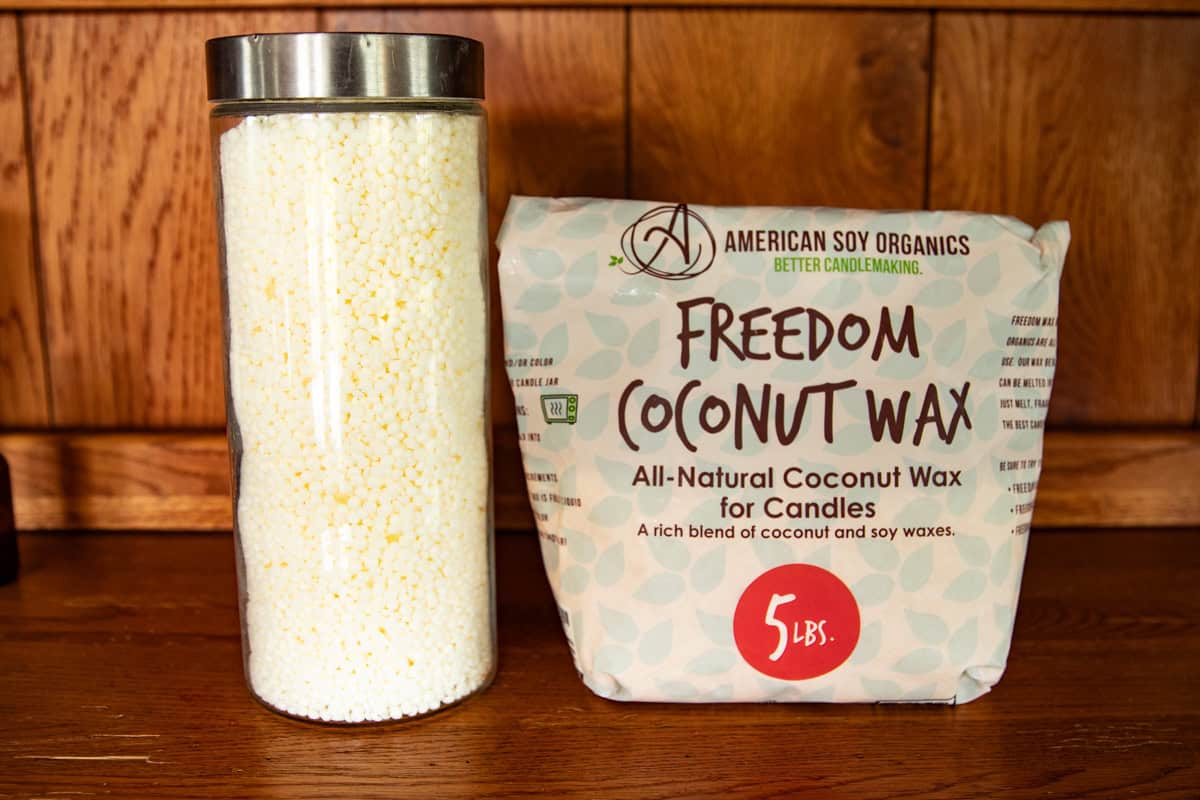 A glass jar filled with wax next to a bulk bag of coconut wax. 