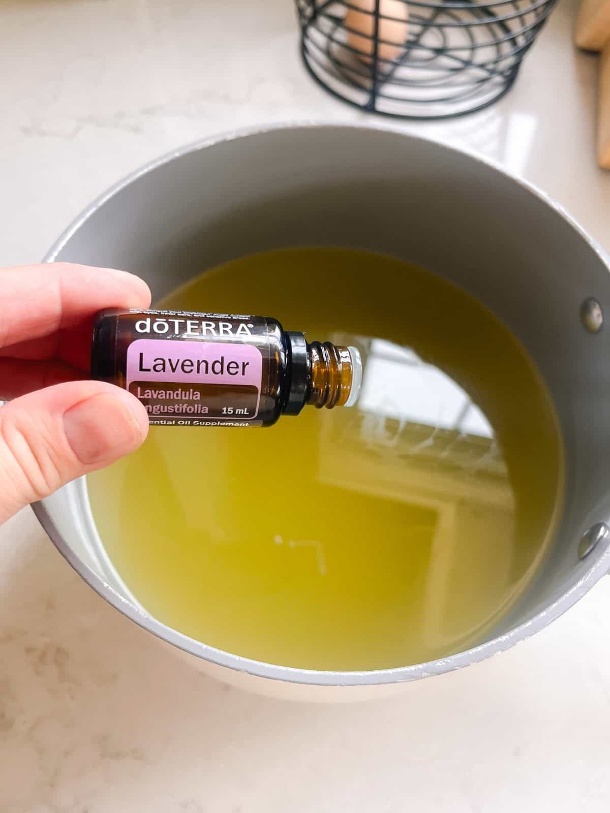 Dropping lavender essential oil into the pot of melted conditioner base and oil.