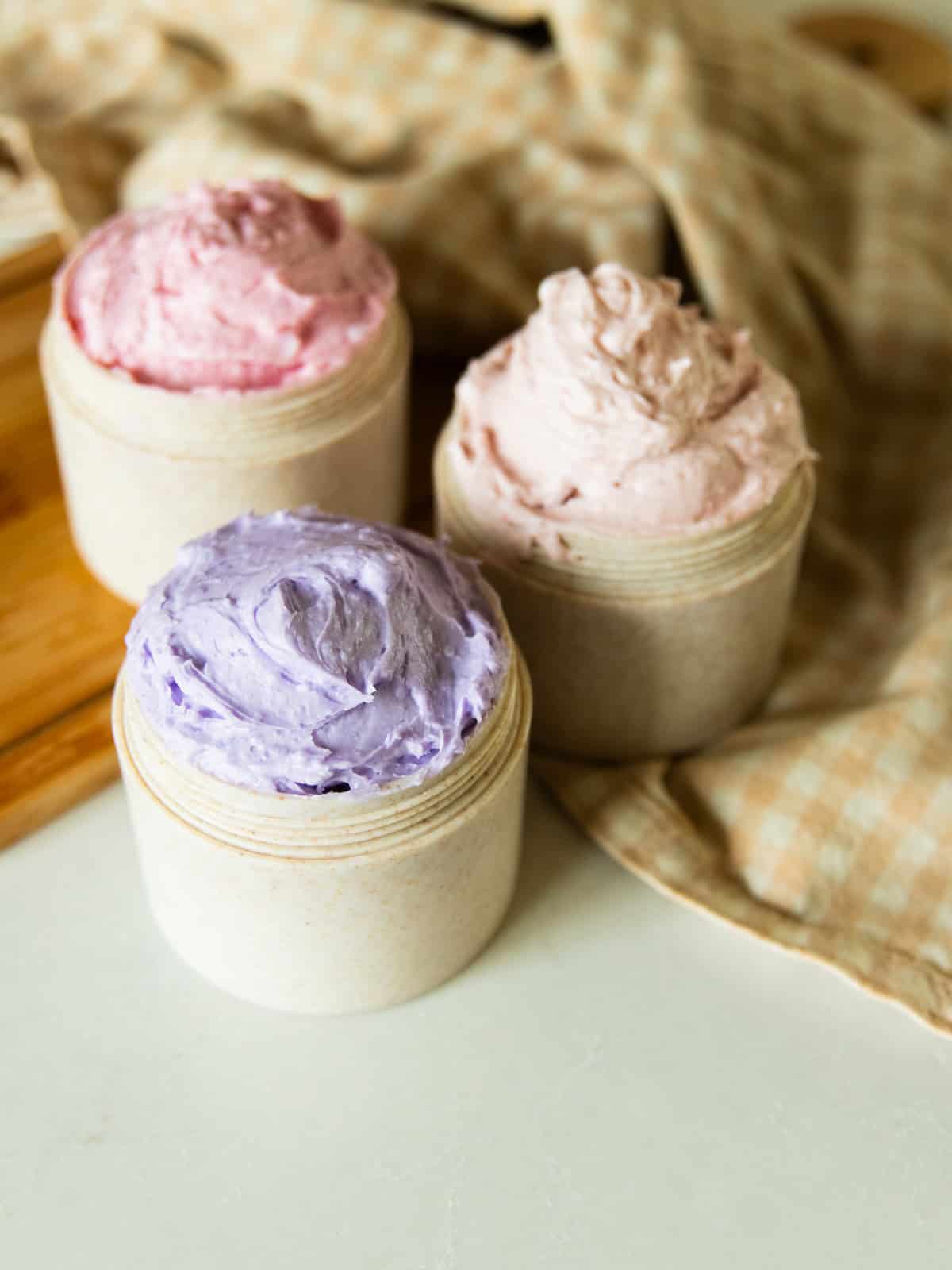 Three jars of foaming sugar scrub: light pink, dark pink, and purple.
