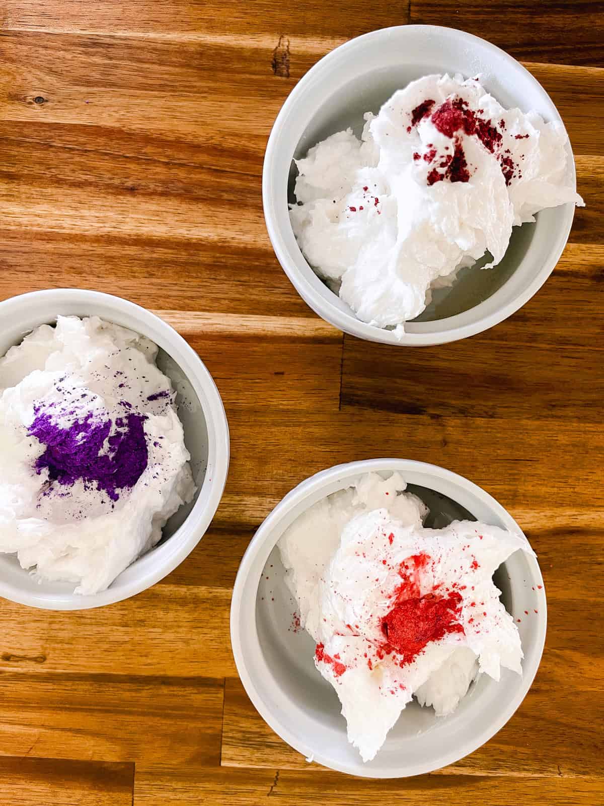 Three bowls of whipped soap base with a scoop of mica powder in each bowl. 