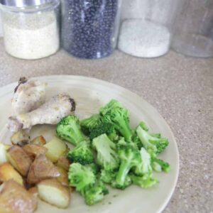 A plate of lemon rosemary chicken dinner with potatoes and broccoli.