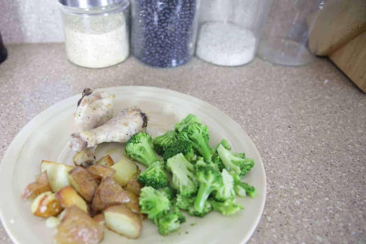 A plate of lemon rosemary chicken dinner with potatoes and broccoli.