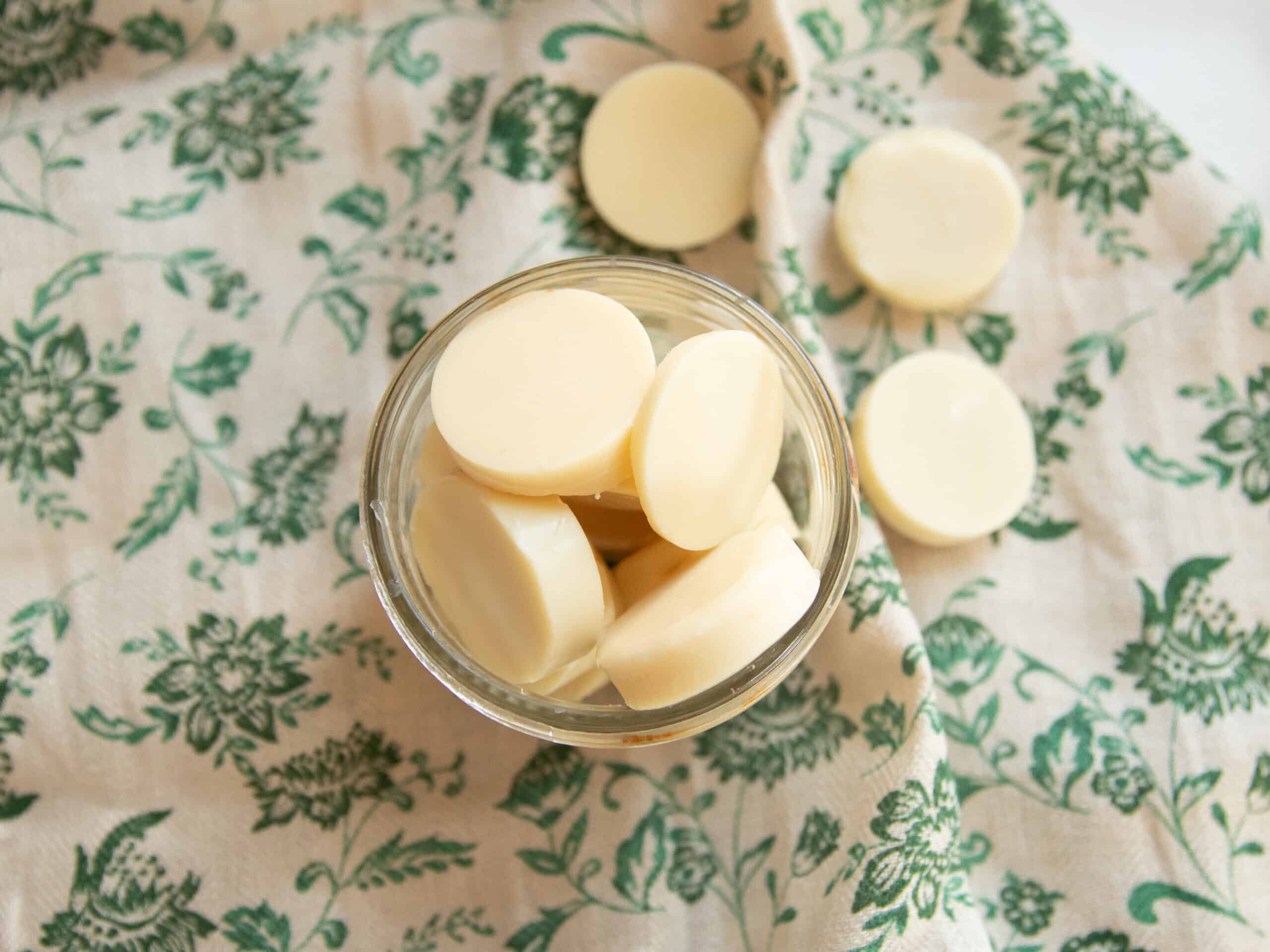 A jar of homemade wax melts on a green flowered towel.