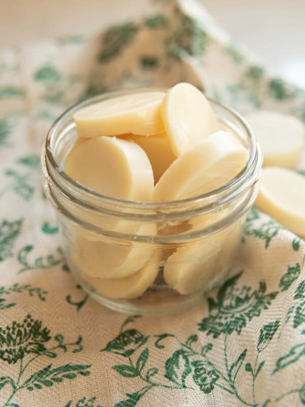 A jar of Christmas wax melts on a green floral towel.