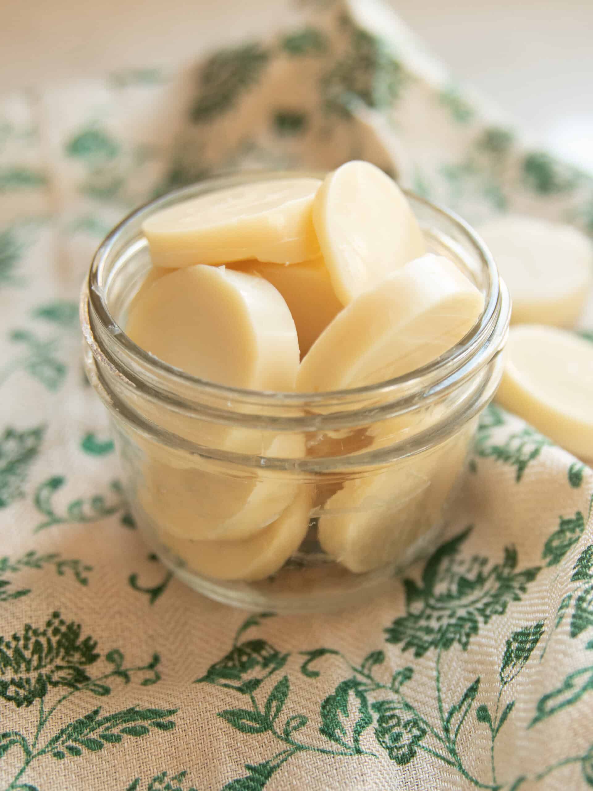 A jar of Christmas wax melts on a green floral towel.