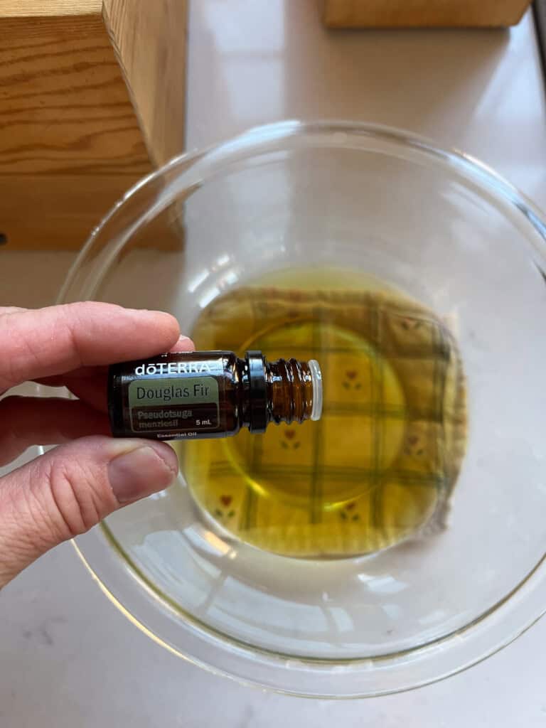 Adding essential oils to a bowl of melted wax.